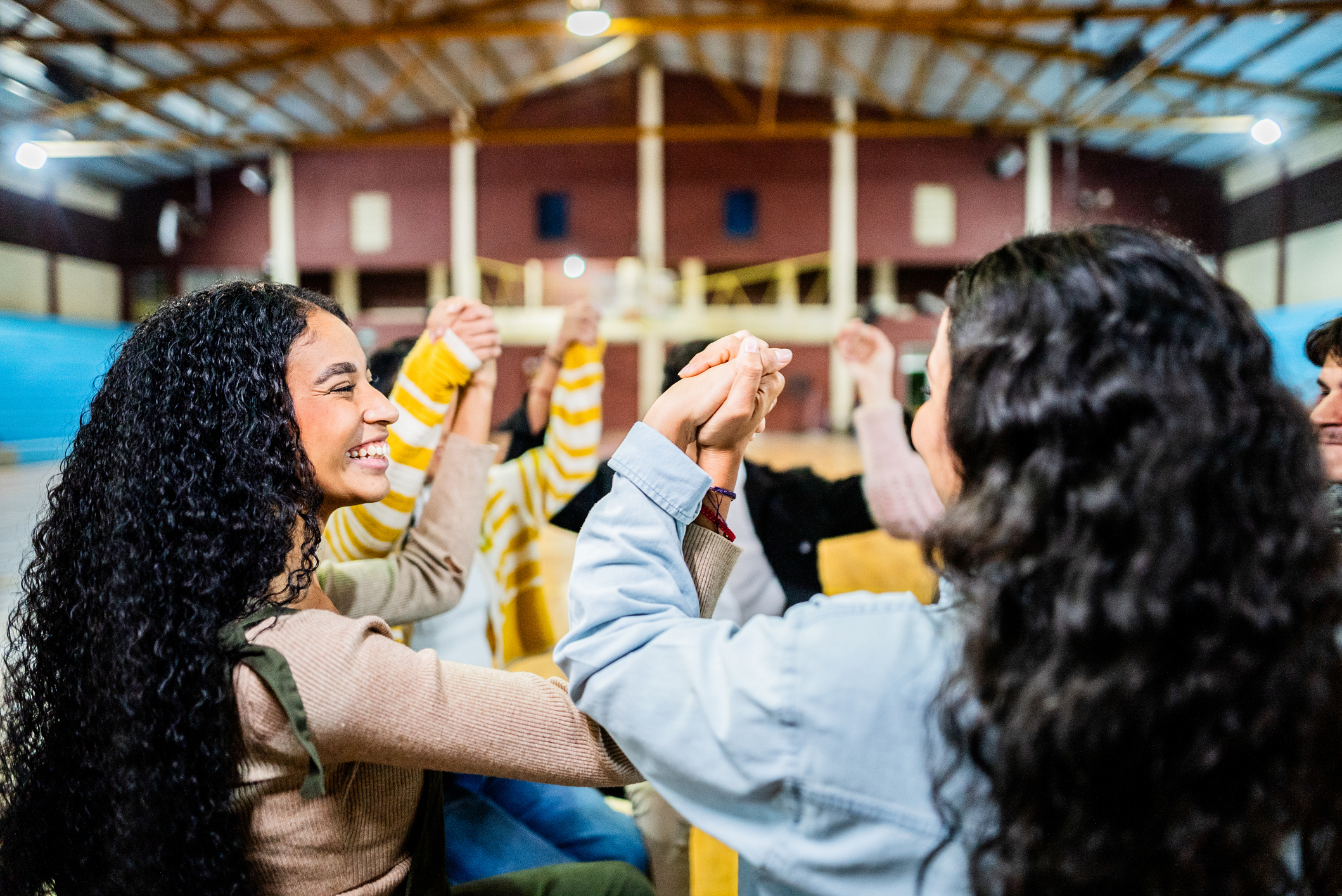 Young people talking and holding hands celebrating during group therapy